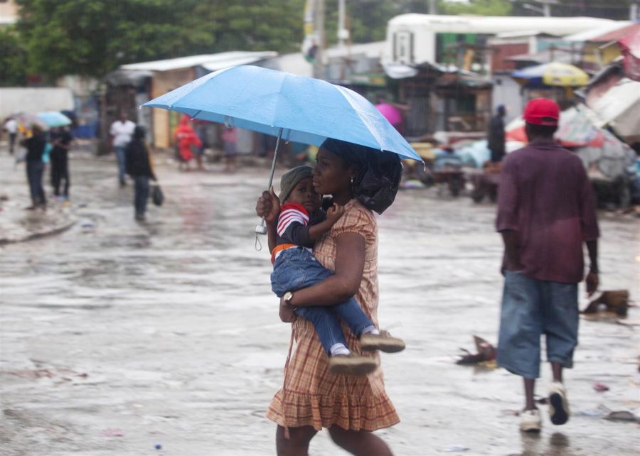 Woman carrying her child in Port-au-Prince walks under the rain caused by Hurricane Matthew